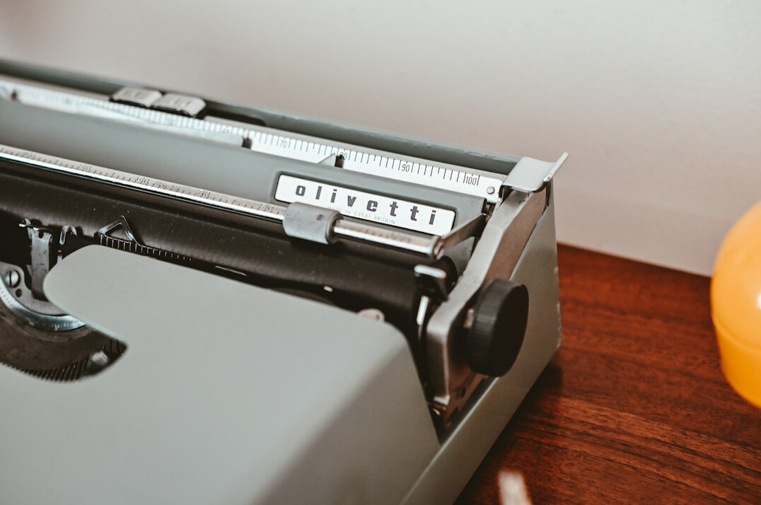 Vintage typewriter with a stack of paper and a cup of coffee on a wooden desk